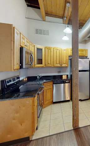 A kitchen with wooden cabinets and a stainless steel refrigerator.