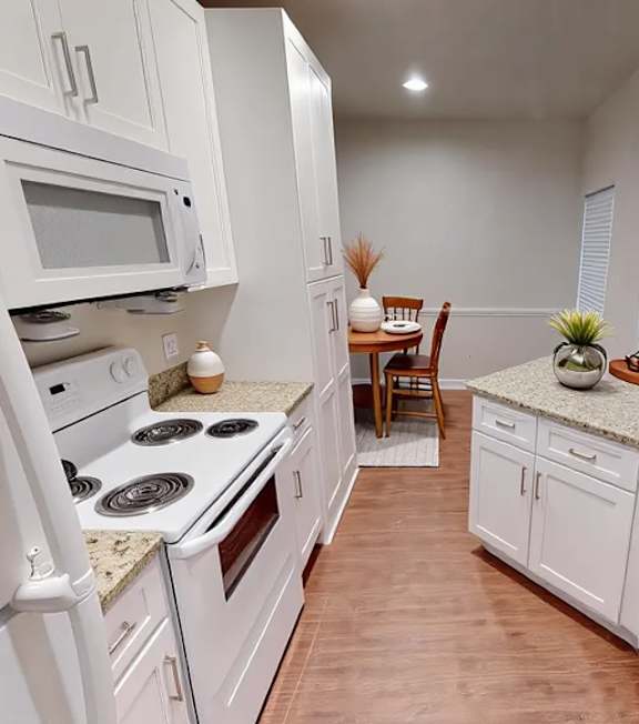 A kitchen with white appliances and cabinets.