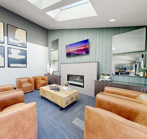 A modern living room with a fireplace and a flat screen TV mounted on the wall at Ellyson Apartment Homes in Tacoma, WA