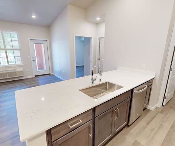 A kitchen with a sink, cabinets, and a window.