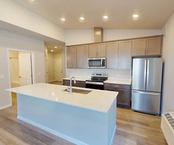 A modern kitchen with a white island and stainless steel appliances.