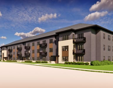 A modern apartment complex with a parking lot in front.