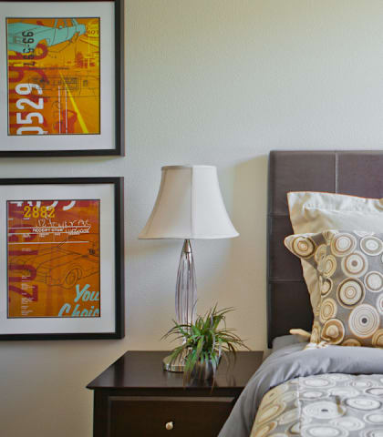 A bed with a grey headboard and a grey comforter with a pillow on it.