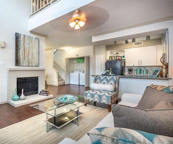 The living room with a couch, plush chairs, coffee table, decorations, a TV, and view of the dining room and the kitchen at Lakewood on the Trail.