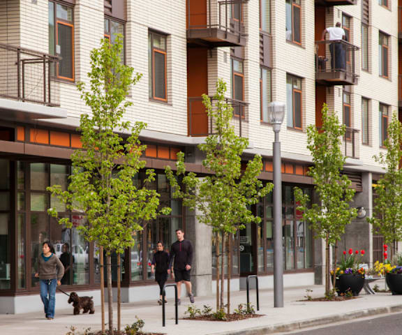 A street view of a building with people walking on the sidewalk.