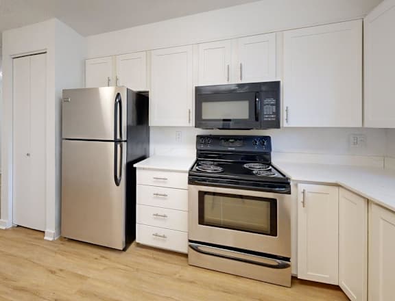 A kitchen with a refrigerator, oven, and microwave.