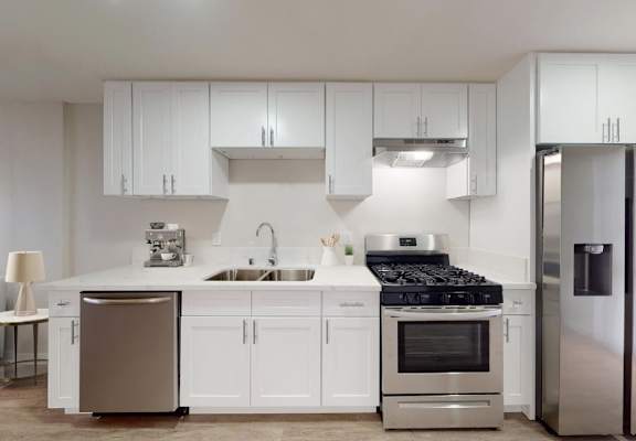 A modern kitchen with white cabinets and stainless steel appliances at Nola 624 Apartments, California