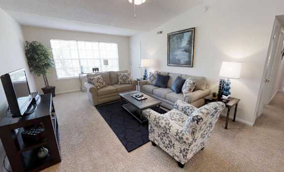 a living room with a couch and chairs and a tv