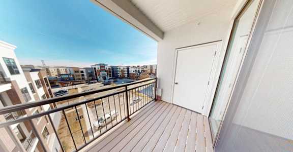 A balcony with a white door and a railing overlooking a cityscape.