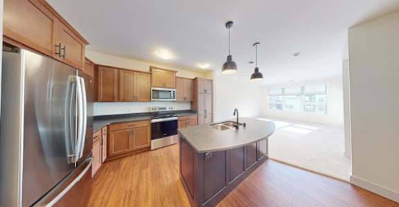 A kitchen with wooden cabinets and a stainless steel refrigerator.