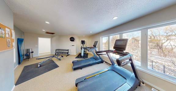 A spacious home gym with a treadmill, exercise bike, and other equipment.