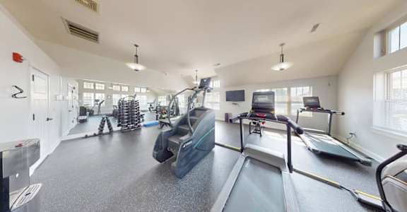 A gym with treadmills, elliptical machines, and other exercise equipment.