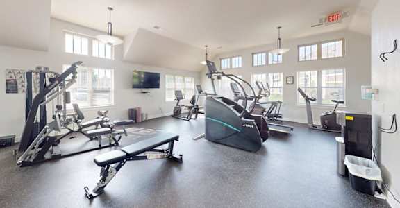 A gym with a variety of exercise equipment including treadmills, stationary bikes, and weight machines.