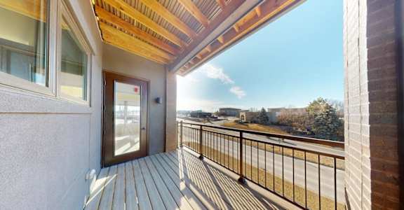 A balcony with a wooden floor and a metal railing.