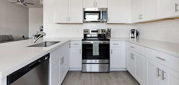 A modern kitchen with white cabinets and stainless steel appliances.