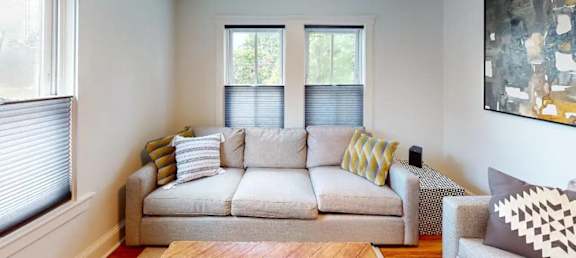 A living room with a couch, pillows, and a painting on the wall.