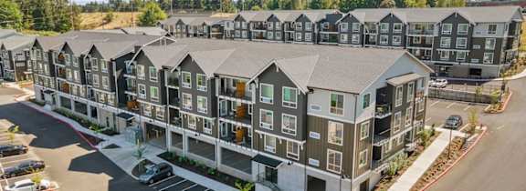 A large apartment complex with a parking lot in front.