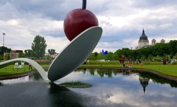 a fountain in a park with a large piece of art on top of it