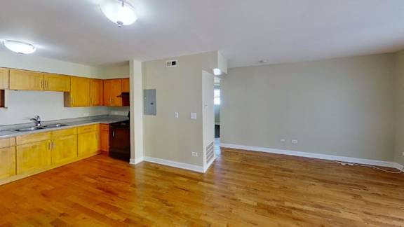 an empty living room and kitchen with wood floors