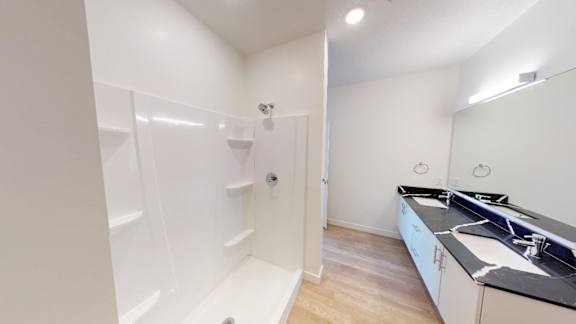A white bathroom with a walk-in shower and a sink.