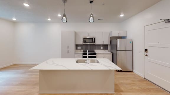 A modern kitchen with a white island and stainless steel appliances.
