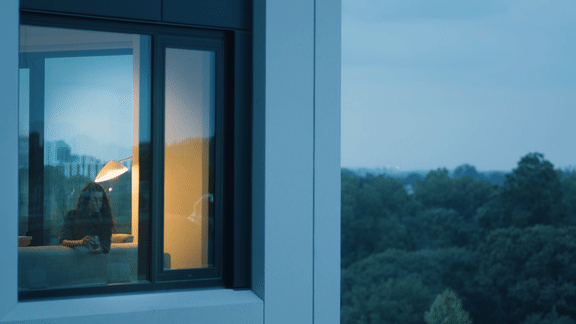 A woman is sitting by a window looking out at the trees1 at Scout Living, powered by Placemakr, Georgia