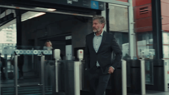 A man in a suit is walking through a turnstile.