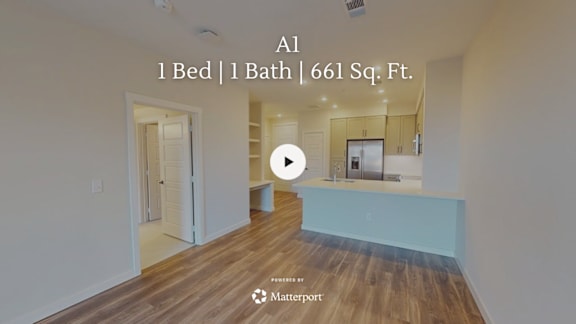 A spacious, empty room with wooden flooring and white walls.