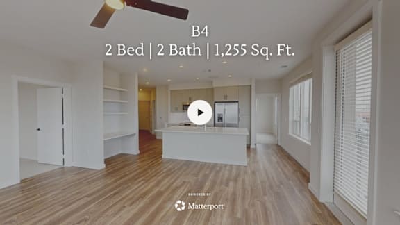 A room with a ceiling fan and a video play button overlay.