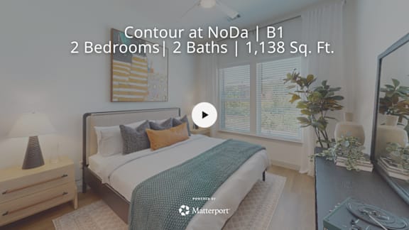 A bedroom with a bed, nightstand, and window.