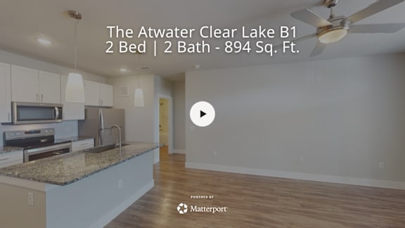 A kitchen with granite countertops and a play button overlay.