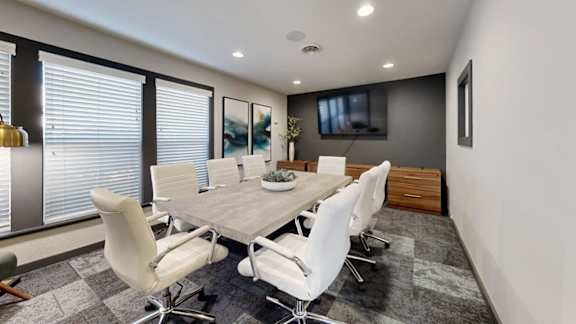 A conference room with a long table and chairs.