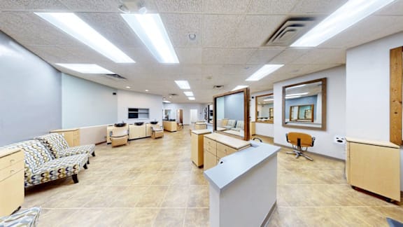 A spacious office room with a desk, chairs, and a couch.