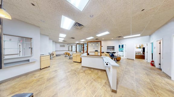 A spacious room with a long table and chairs in the center.