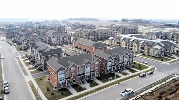 A row of houses with cars parked in front.