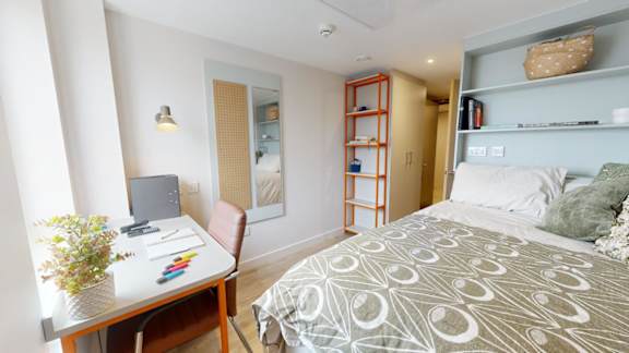 A bedroom with a bed, desk, and chair.