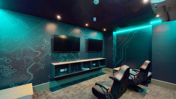 a gaming room with two chairs and two televisions