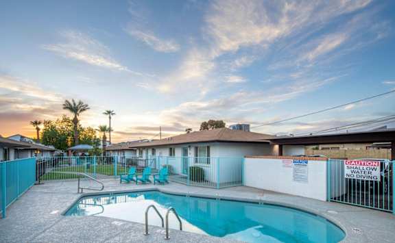 a swimming pool with a fence and a house with a pool
