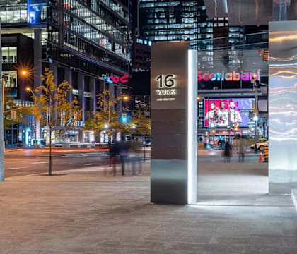 A tall, modern structure with the number 16 on it stands in a city plaza.