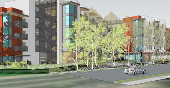 A car is parked on the side of a road in front of a row of buildings.