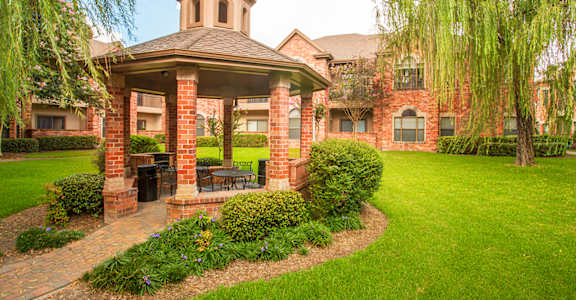 a gazebo with a picnic table in front of a building