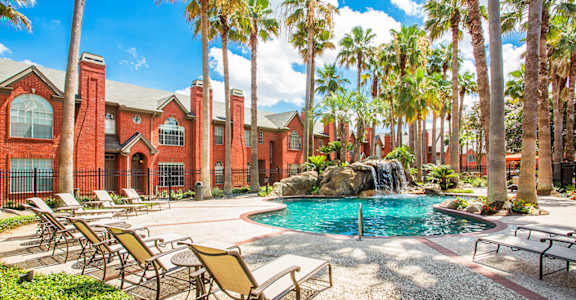 a pool with chairs and a waterfall in front of a building