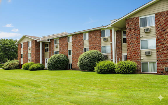 A row of red brick apartment buildings with green bushes in front.