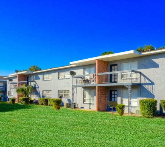 A row of modern apartment buildings with green lawns in front  at Hibiscus Place Apartments in Orlando, FL, 32808