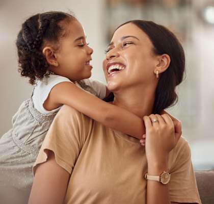 A woman is hugging a child from behind.