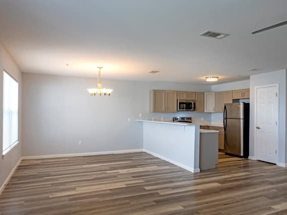 an empty living room and kitchen with a refrigerator and a sink