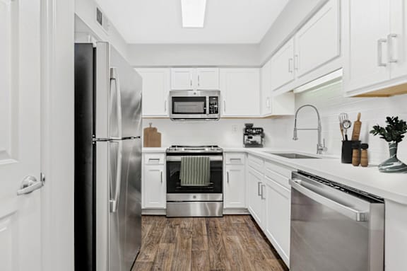 a kitchen with white cabinetry and stainless steel appliances at Caveness Farms Apartments, Wake Forest, NC 27587