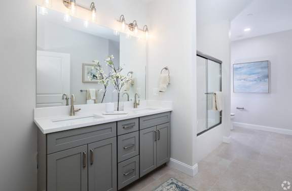 A bathroom with a vanity, a mirror, and lights.