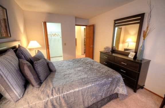 a bedroom with a large bed and a dresser and a bathroom