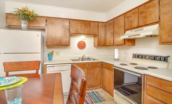A kitchen with wooden cabinets and a white stove top oven.